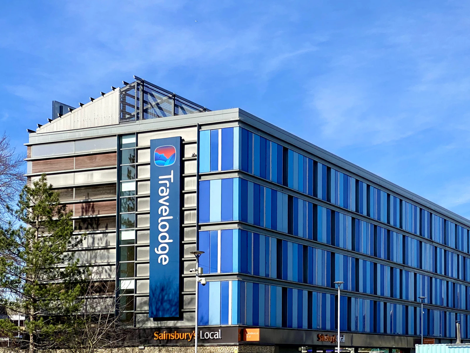 Travelodge Cambridge Central entrance facing the Cambridge Leisure Park, with restaurants and the Cambridge Junction entertainment venue visible opposite