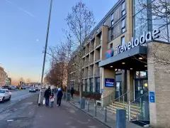 Travelodge Cambridge Newmarket Road exterior on a busy trunk road, with the Premier Inn visible to the right and the Petersfield neighbourhood behind